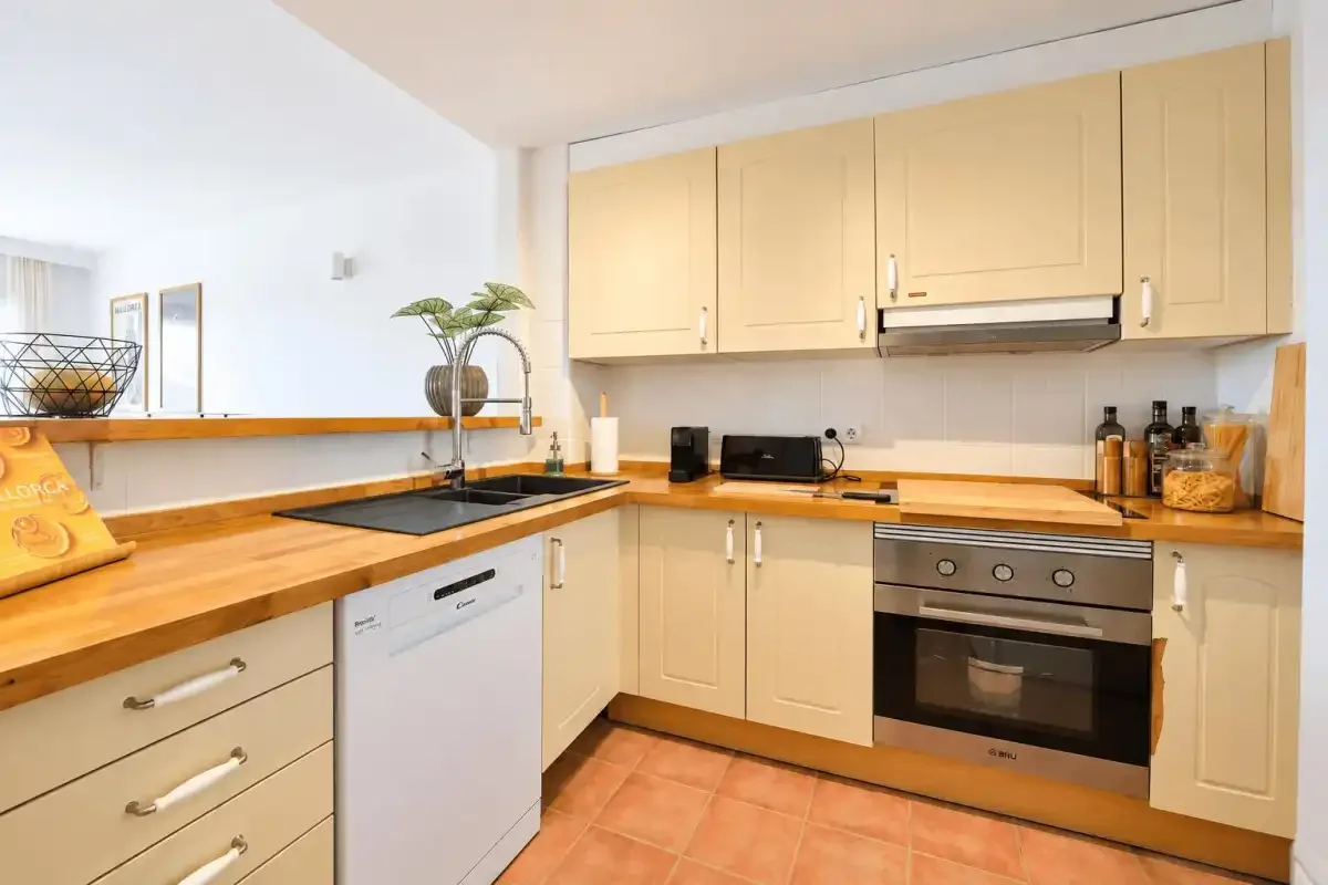 A bright kitchen with pale cabinets, wooden countertops, and a built-in oven.