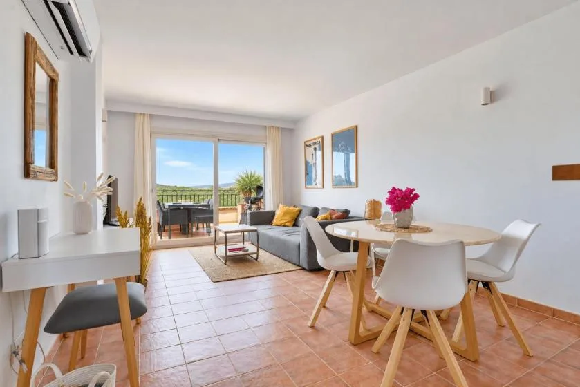 A bright living and dining area opens onto a balcony through large glass doors.