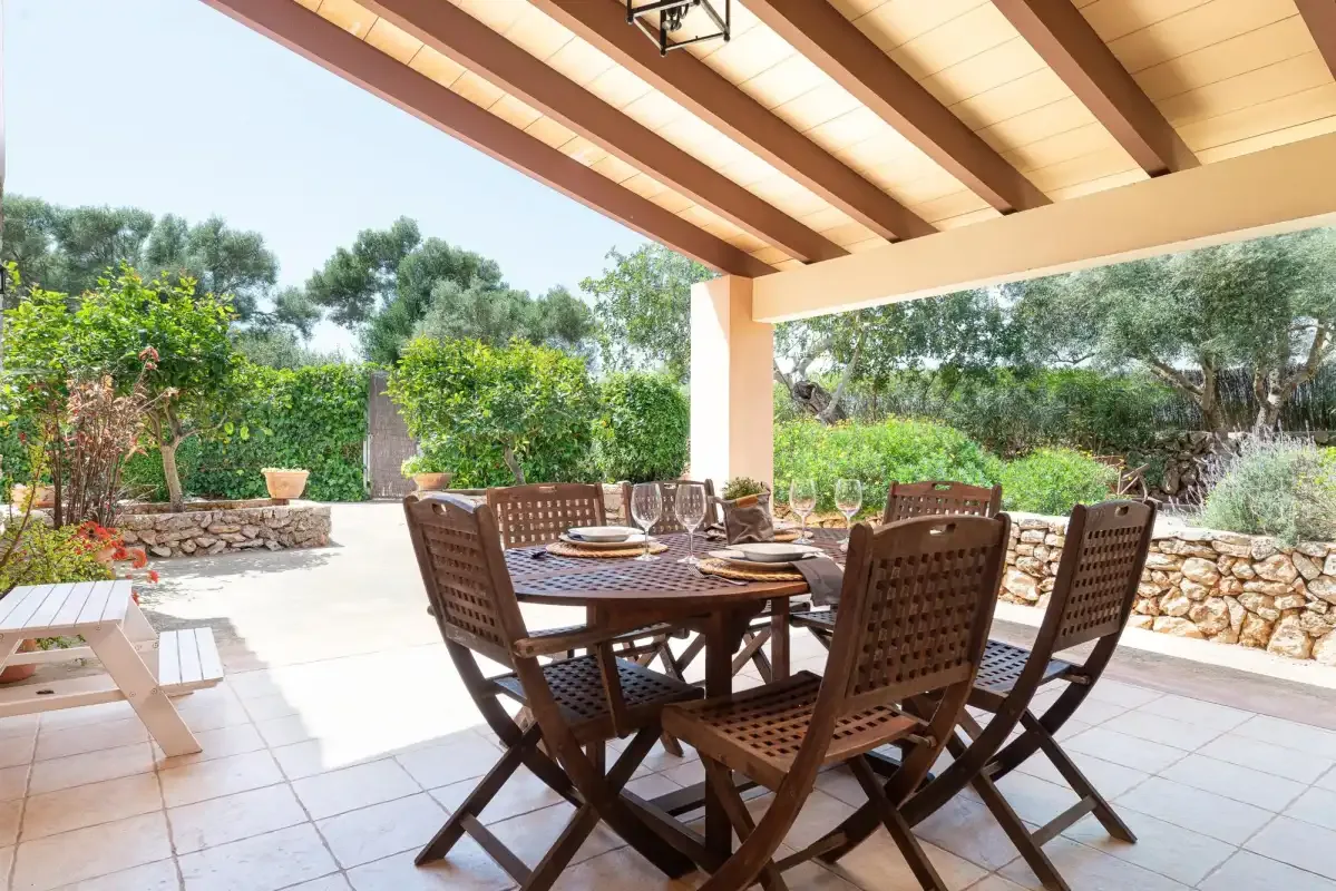 A covered patio dining area with a wooden table and garden views.