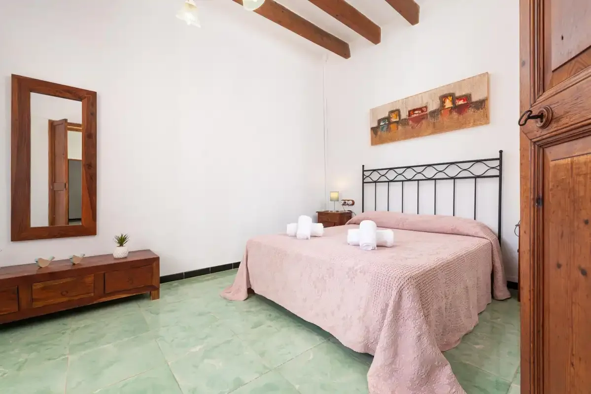 A bedroom with a double bed and wooden furnishings.