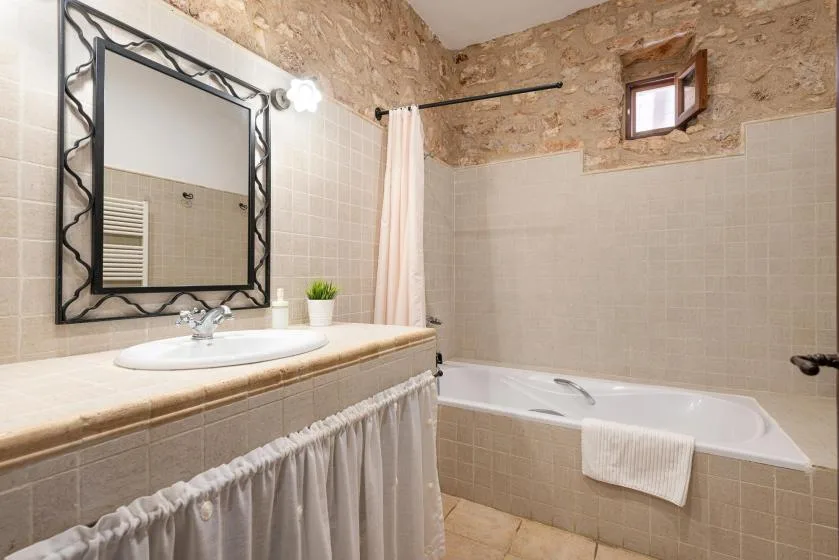 A bathroom with a bathtub, sink, and wall mirror.