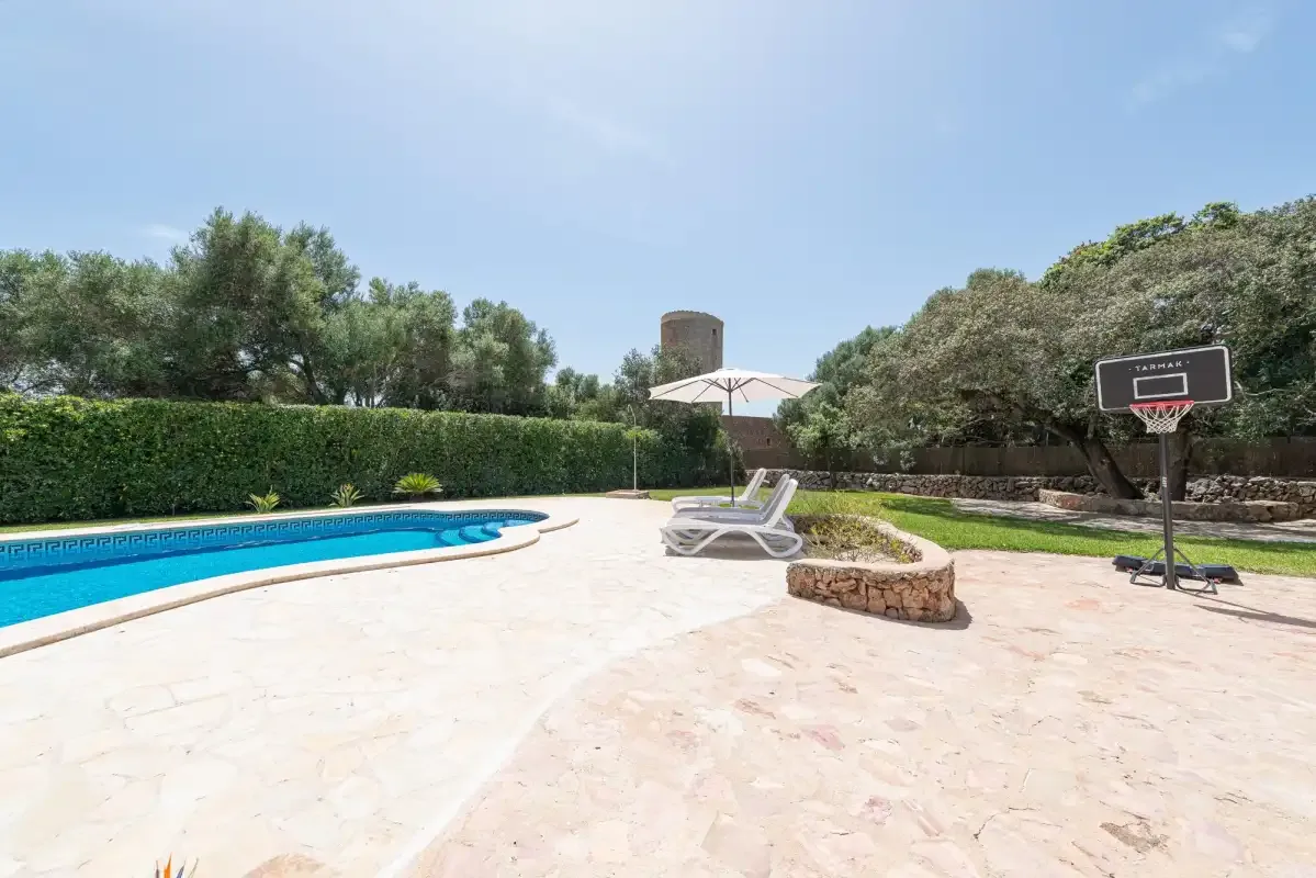 An outdoor pool area with a basketball hoop and sun loungers.
