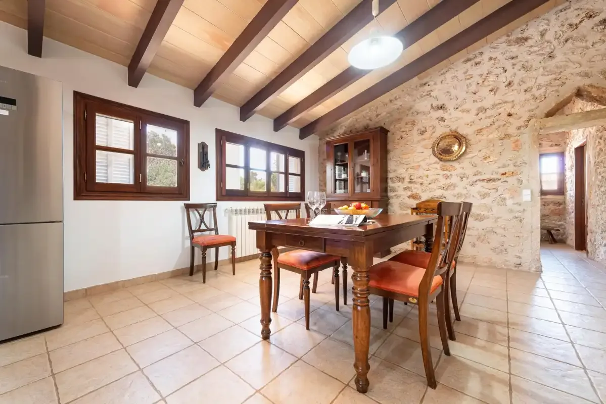 A dining area with a wooden table and chairs beneath exposed ceiling beams.
