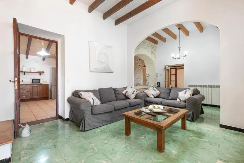 A living room with gray seating and a wooden coffee table beneath exposed ceiling beams.