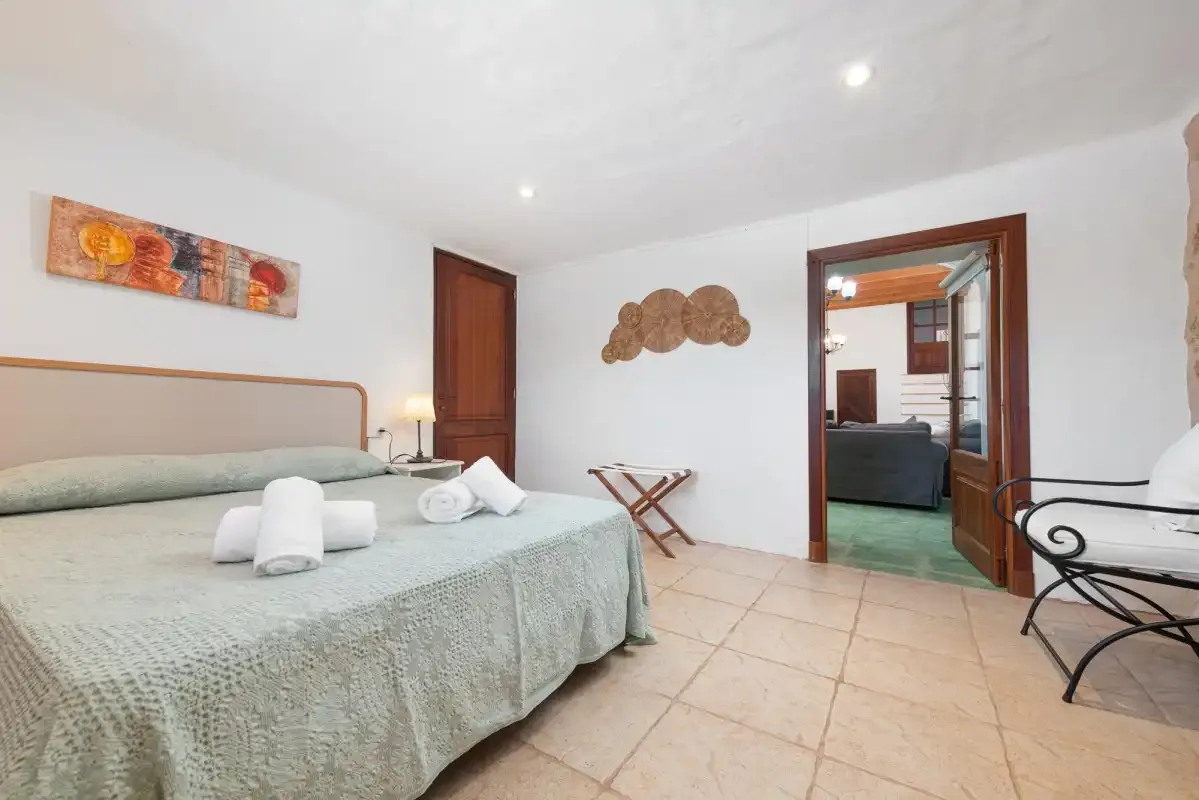 A bedroom with a double bed and an open doorway leading to another room.