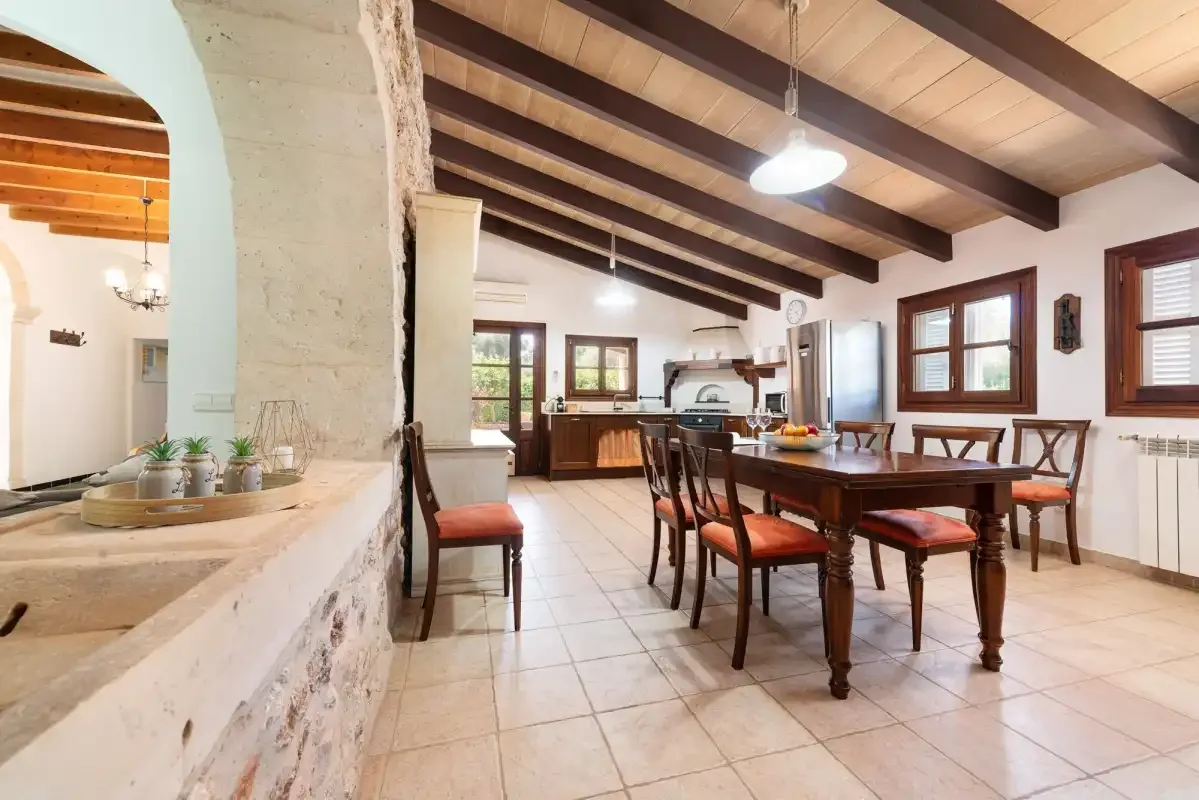 A dining area with a wooden table and chairs beside an open kitchen.
