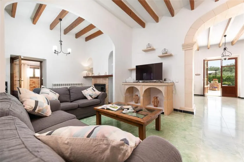 A bright living room with sectional seating, a coffee table, and a television.
