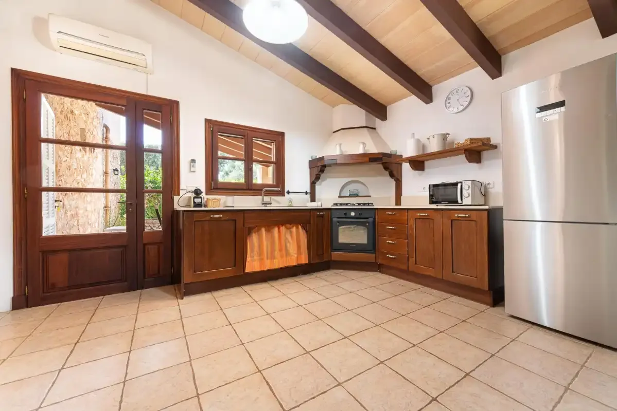 A kitchen with wooden cabinets, a tiled floor, and a stainless steel refrigerator.