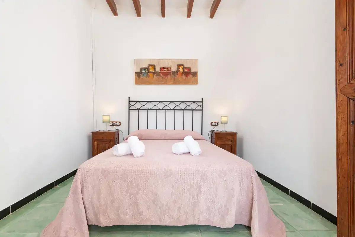 A bedroom with a double bed, bedside tables, and exposed ceiling beams.