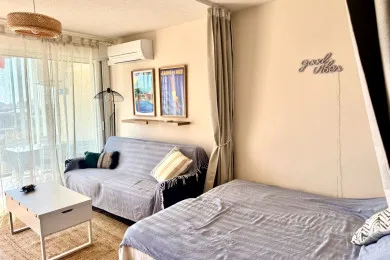 A bright bedroom with a bed, sofa, and large windows.