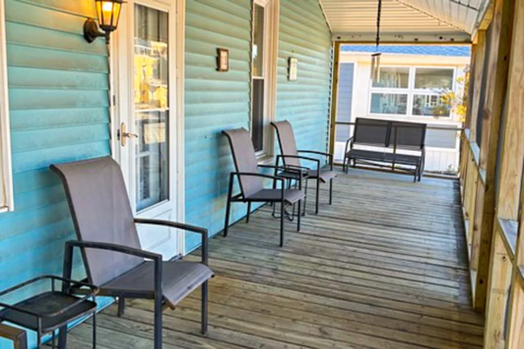 A covered porch with seating and a wooden deck.