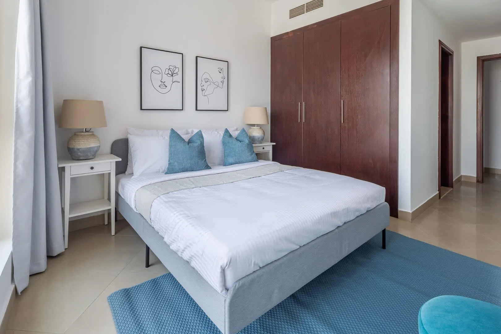 Un dormitorio luminoso con una cama bien tendida y un gran armario de madera.