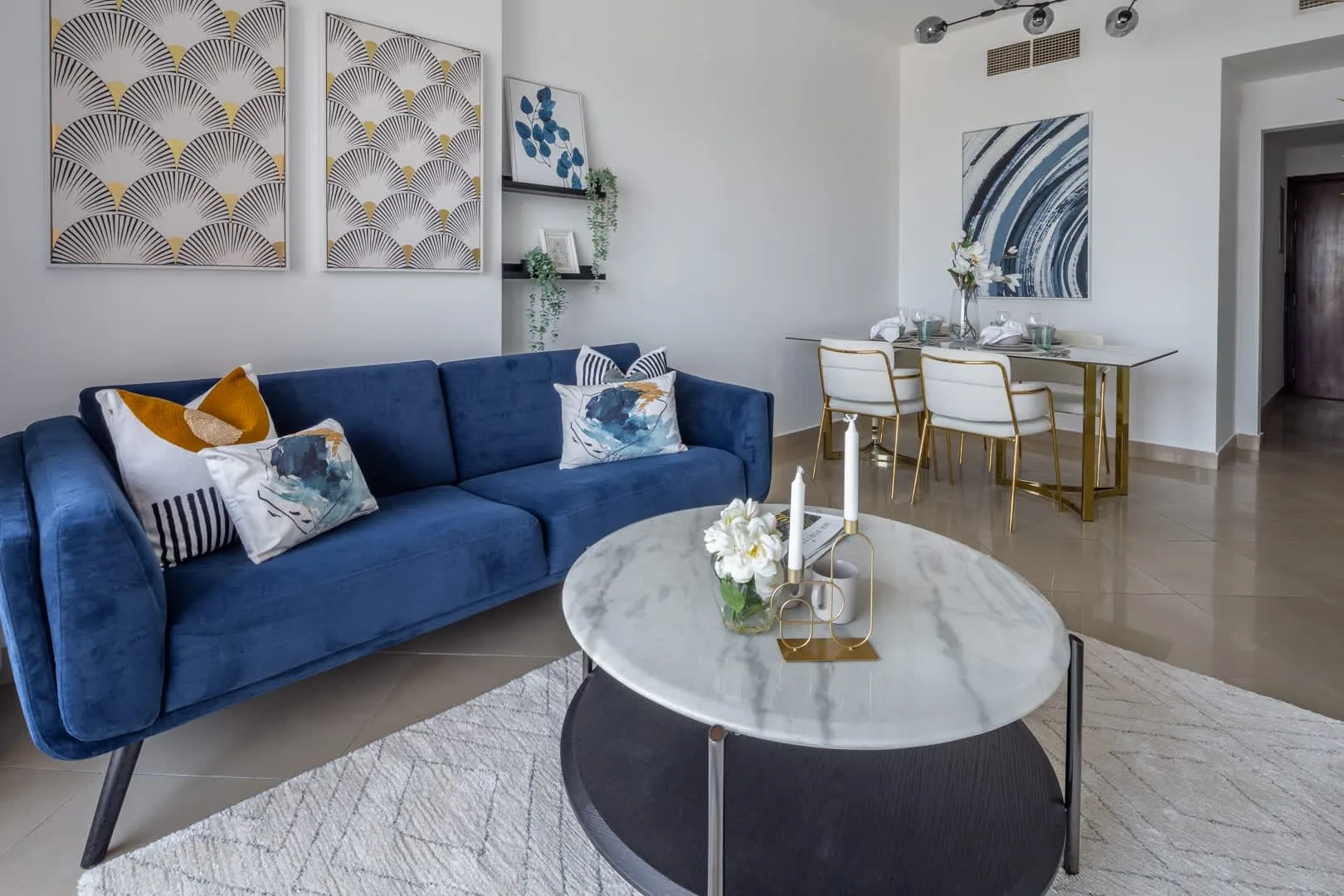 Una sala de estar y comedor con asientos azules y una mesa preparada para comer.