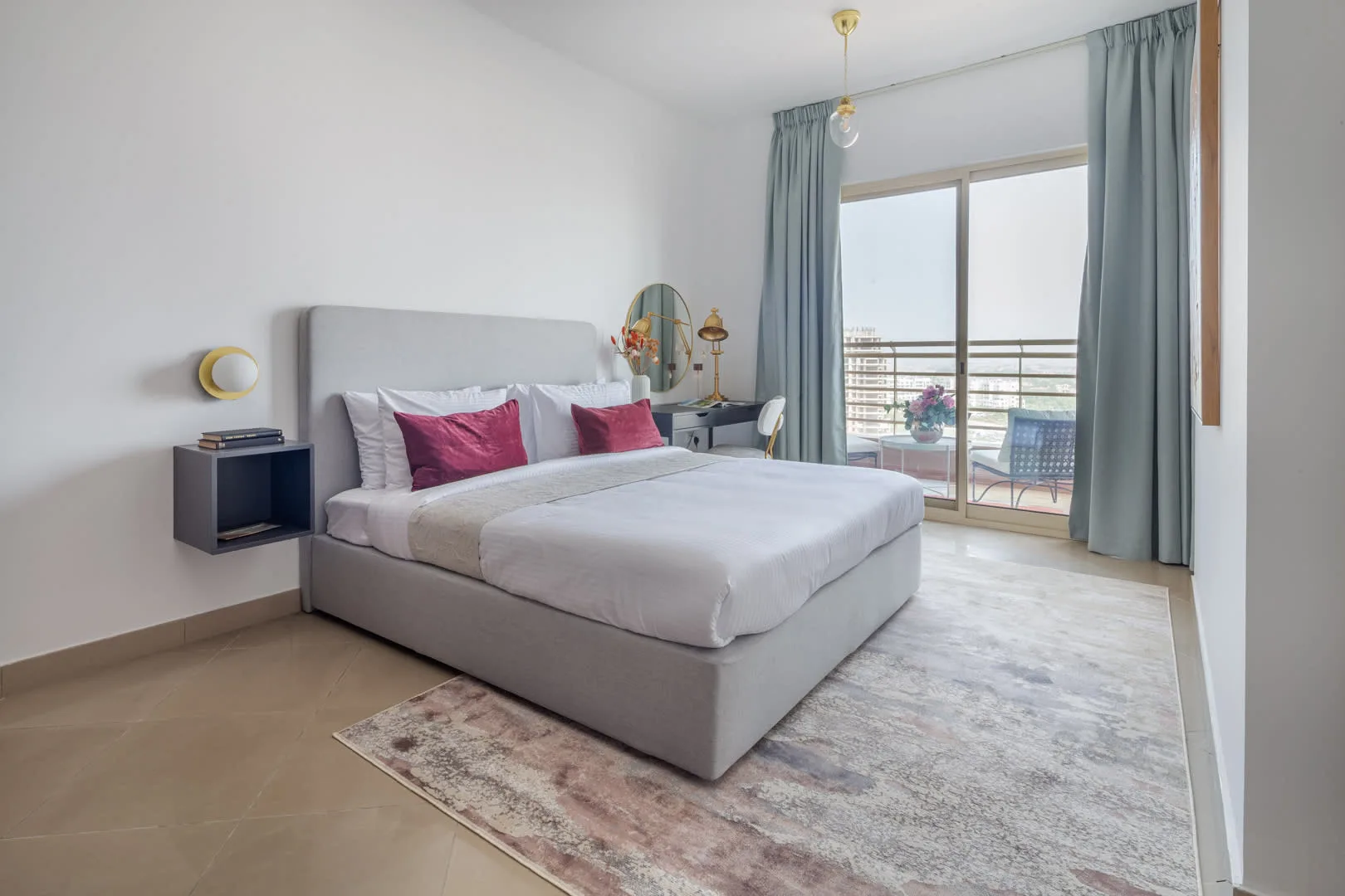 Un dormitorio luminoso cuenta con una cama grande junto a puertas de vidrio con cortinas.