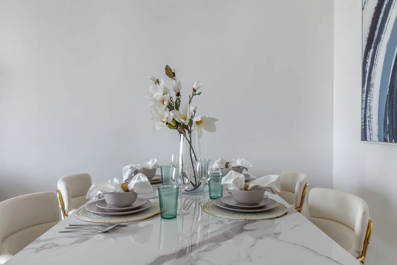 Comedor con la mesa puesta y un jarrón con flores.