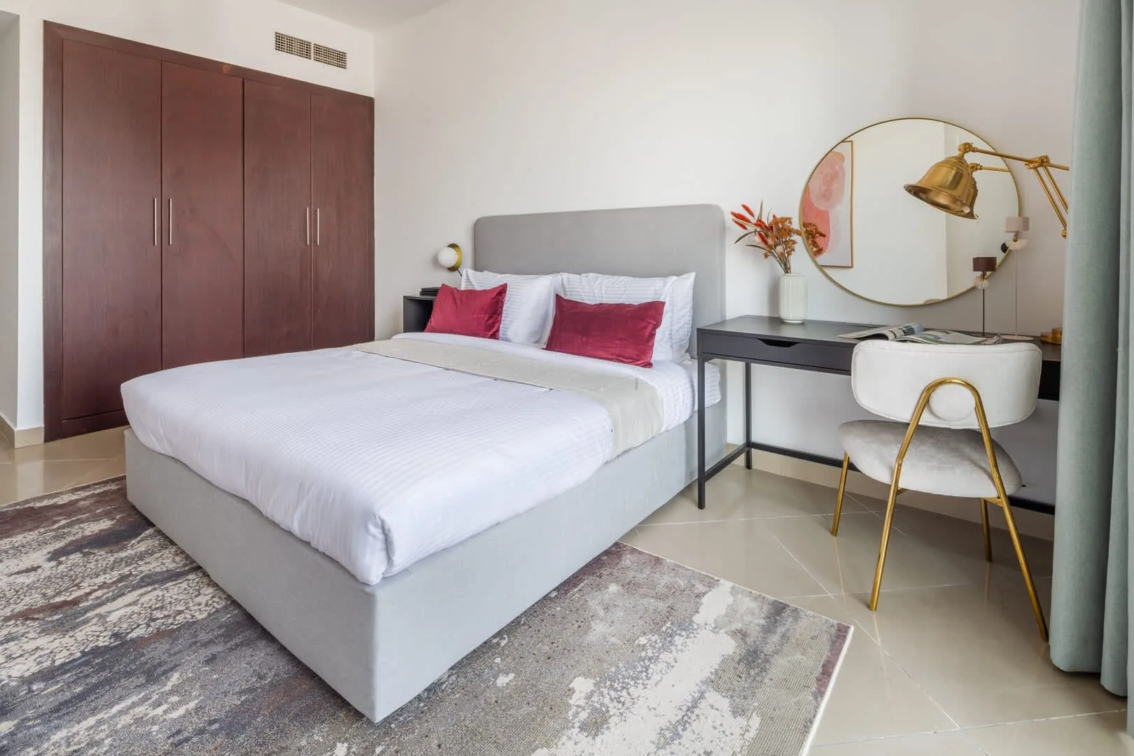 Un dormitorio con una cama bien tendida y un escritorio al lado.