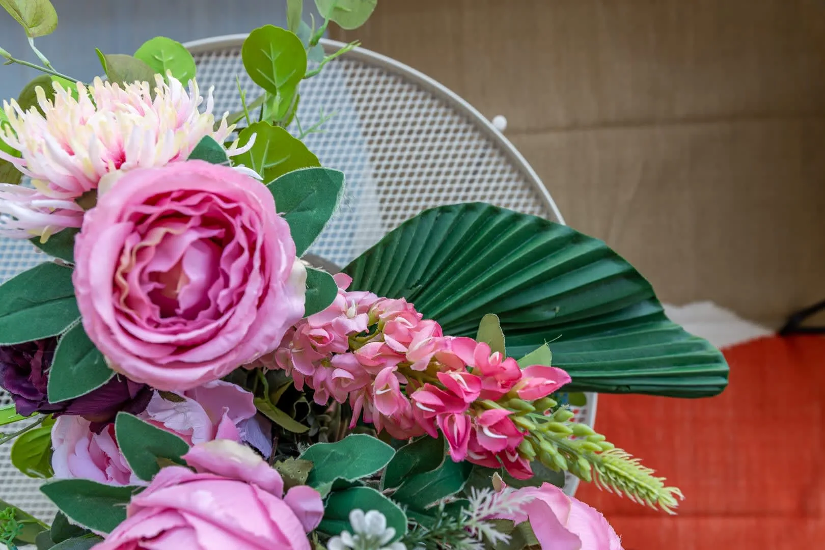 Un arreglo floral con flores rosas y hojas verdes ocupa el primer plano.
