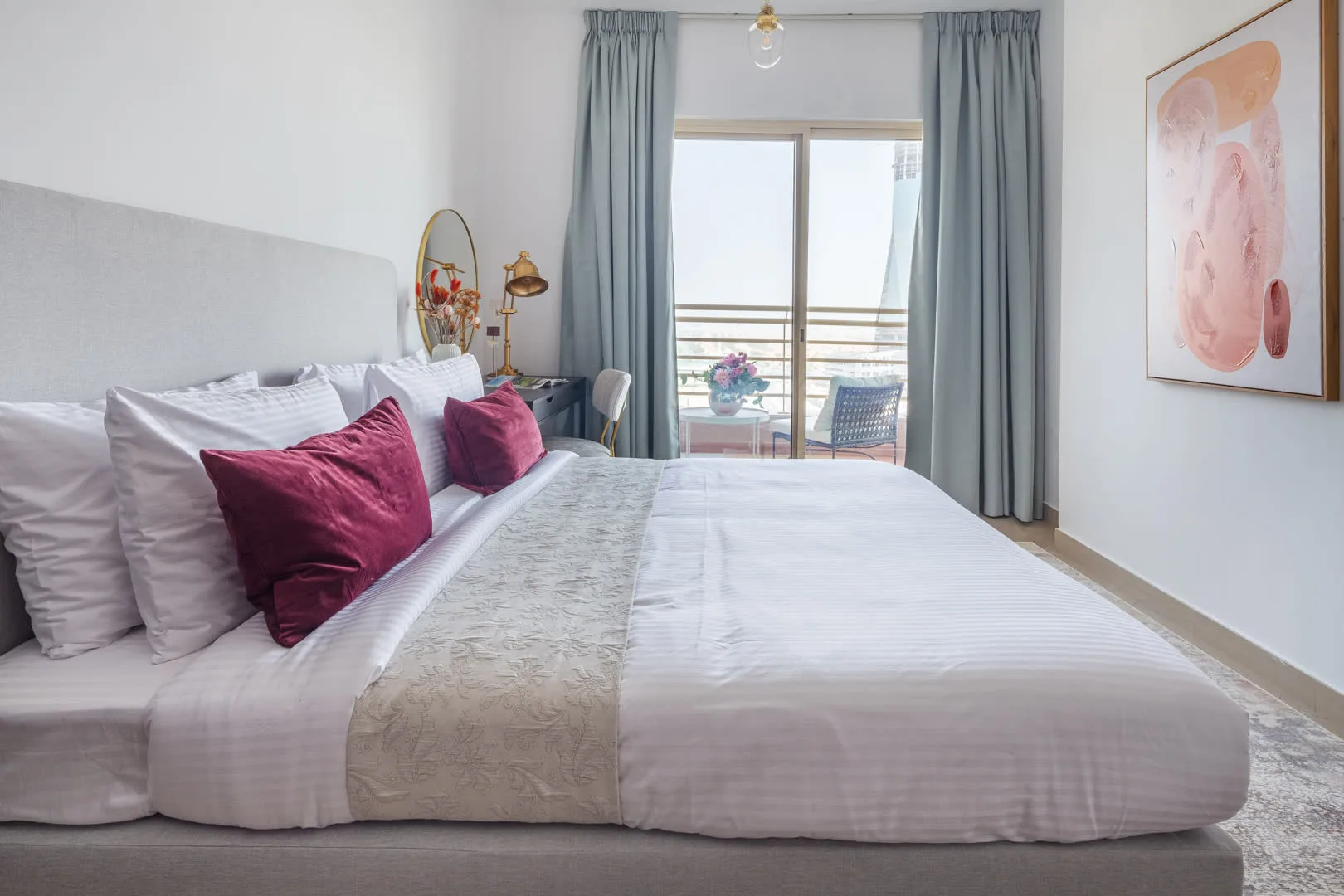 Un dormitorio luminoso con una cama bien hecha y cortinas azules junto a la ventana.