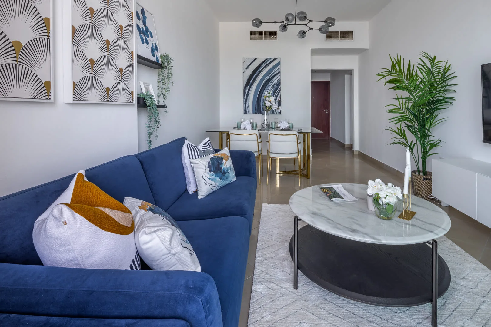 Una sala de estar moderna con asientos azules y una mesa de centro redonda.