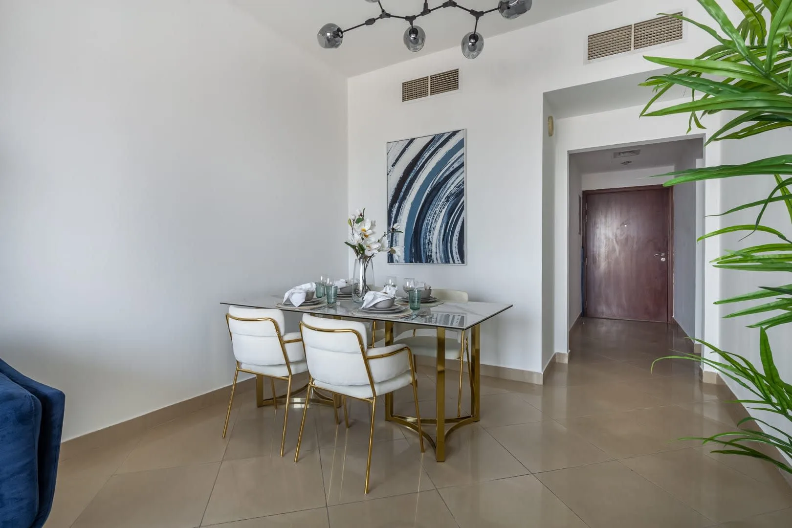 Un comedor con una mesa de vidrio, sillas y arte abstracto en la pared.