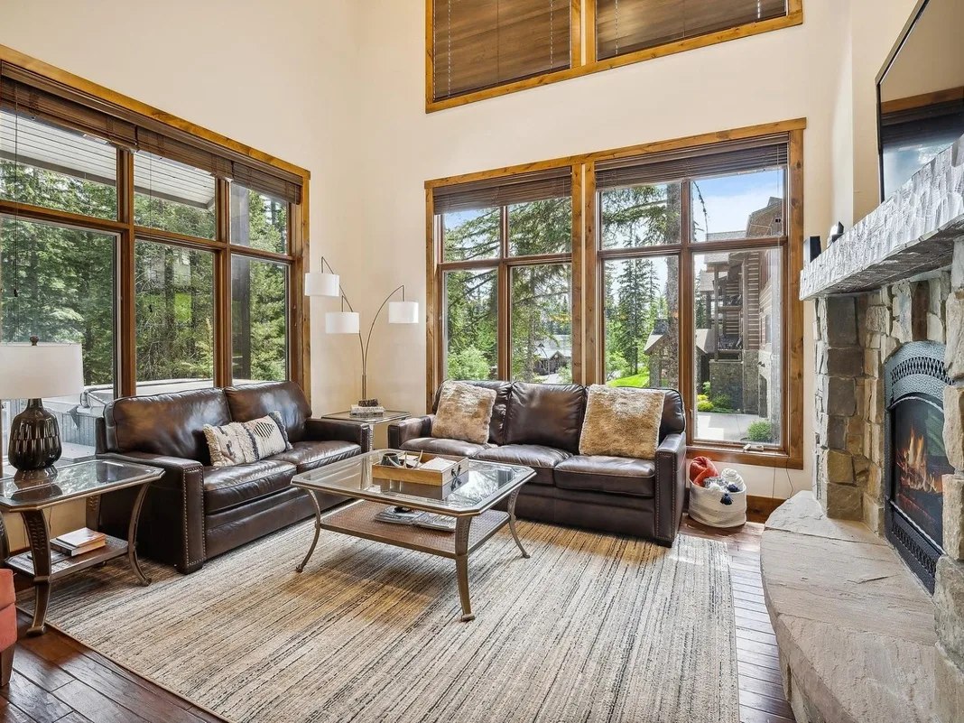Una sala de estar con asientos de cuero, grandes ventanas y una chimenea.