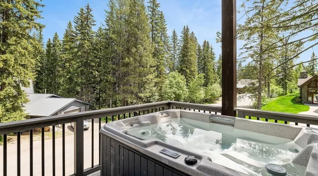 Una bañera de hidromasaje al aire libre está en una terraza con vistas a un paisaje boscoso.