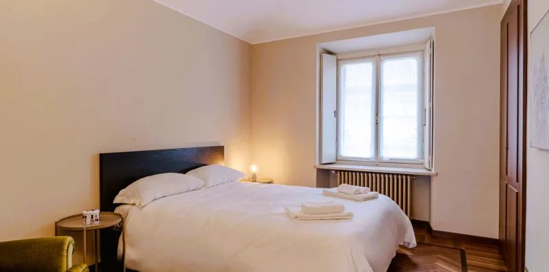 A bedroom with a neatly made bed beneath a window.