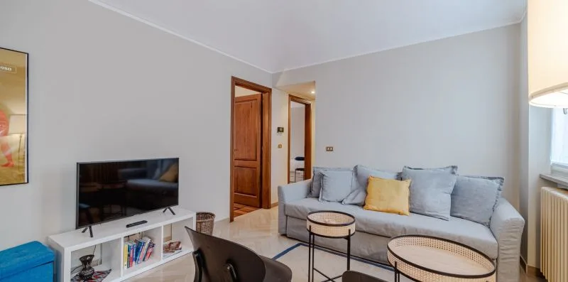 Una sala de estar con un sofá gris, un televisor y mesas de centro.