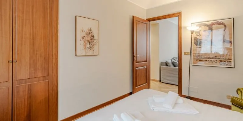 Un dormitorio con una cama ordenada y una puerta abierta.