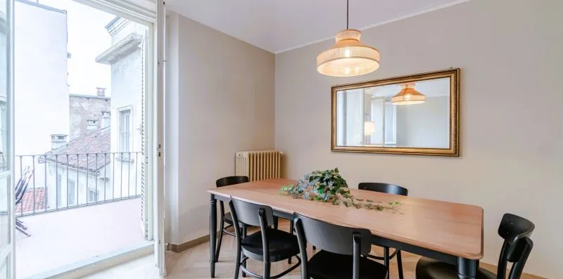 Comedor con una mesa de madera y un espejo grande en la pared.