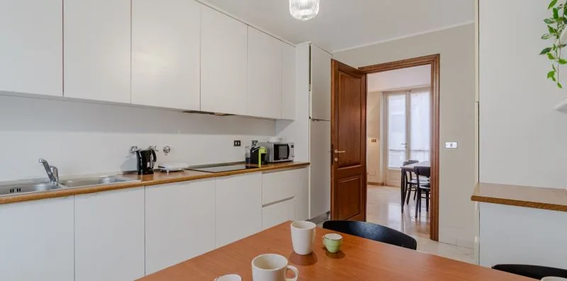 Una cocina luminosa con gabinetes blancos y una encimera de madera.
