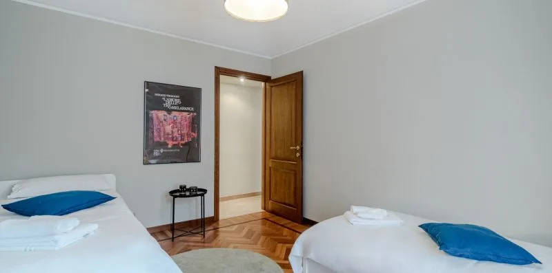 Un dormitorio con dos camas y una puerta de madera abierta hacia un pasillo.