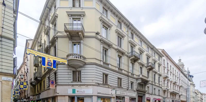 Una esquina urbana con un edificio de varias plantas y locales comerciales.