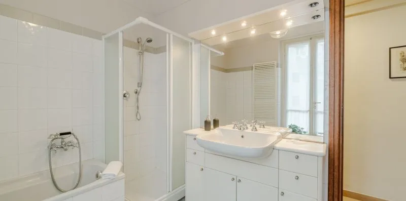 Un baño luminoso con bañera, ducha y tocador.