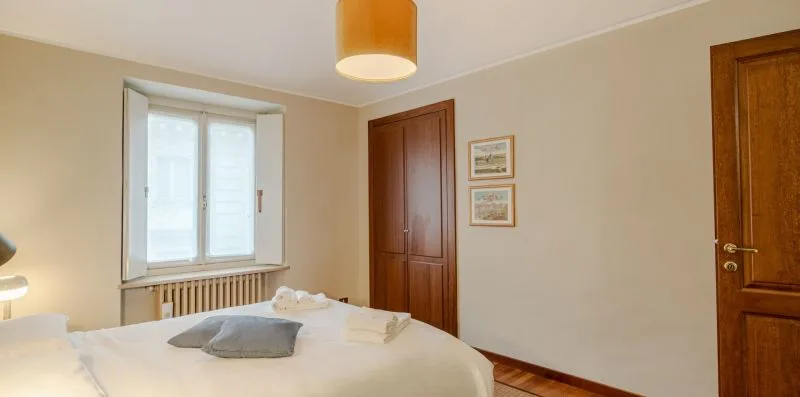 Un dormitorio con una cama, una ventana y puertas de madera.