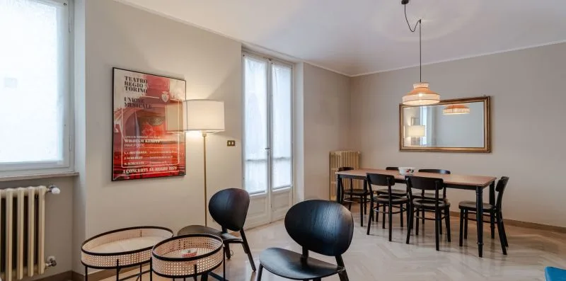 Comedor con una mesa y sillas junto a ventanas altas.