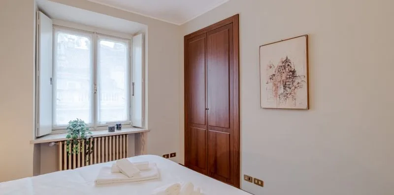 Un dormitorio con una cama, una ventana y un armario de madera.