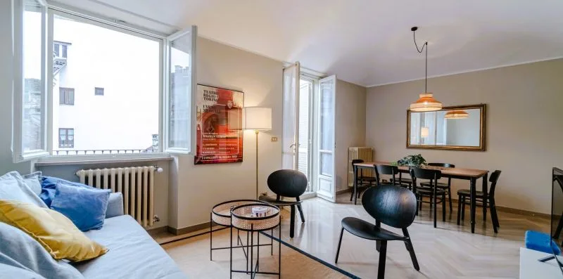 A bright living and dining area with seating beside large windows.