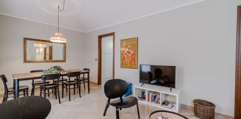 A dining and living area with a table, chairs, and television.
