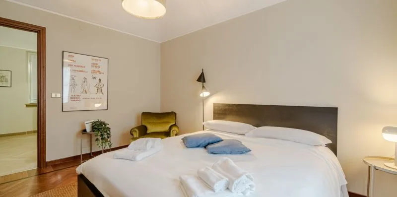 Un dormitorio con una cama bien tendida y lámparas de noche.