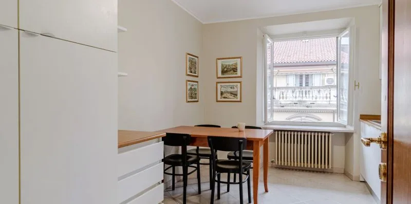 Un pequeño comedor con una mesa y sillas junto a una ventana grande.