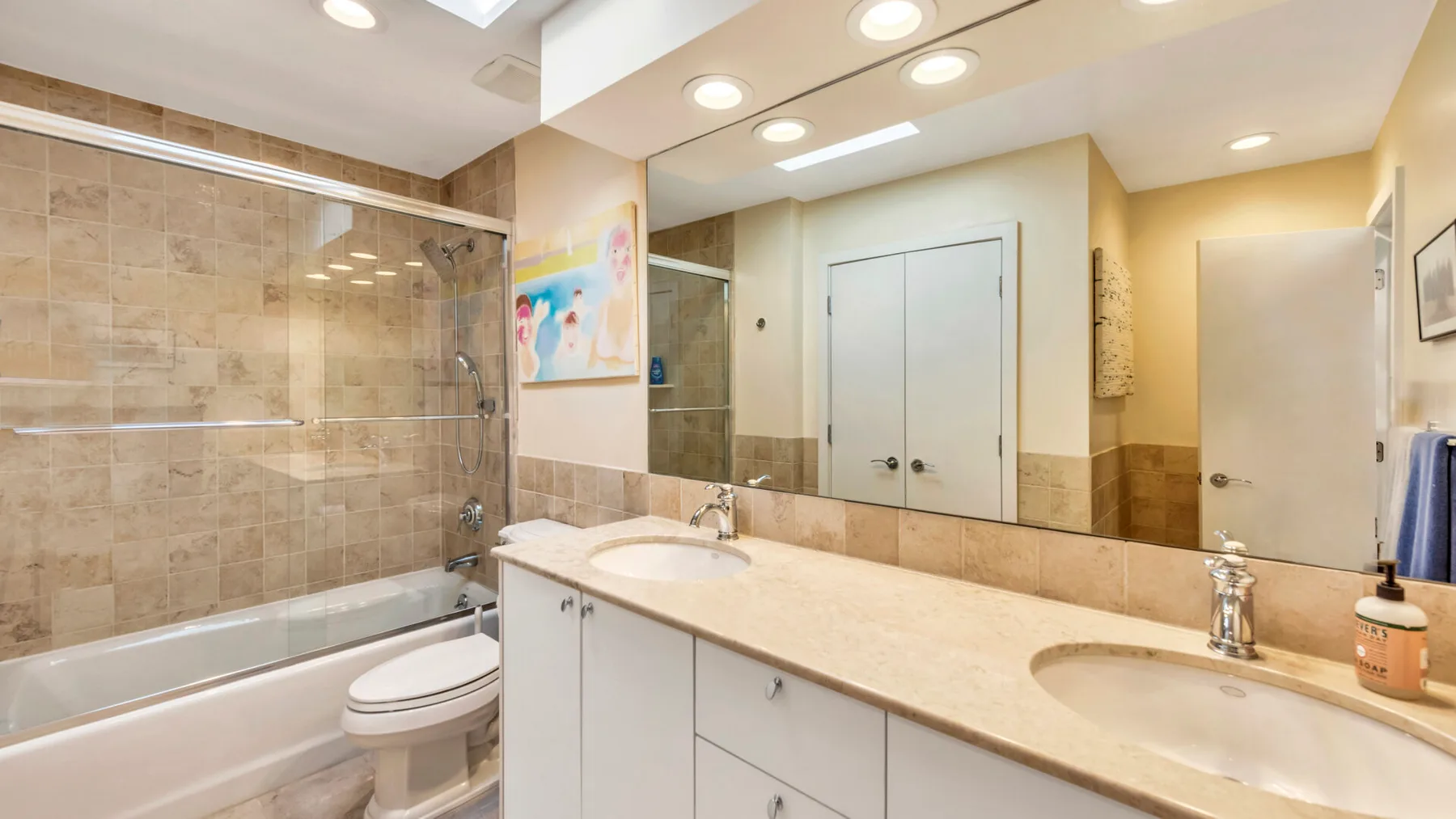 A bright bathroom with a long vanity, two sinks, and a bathtub.