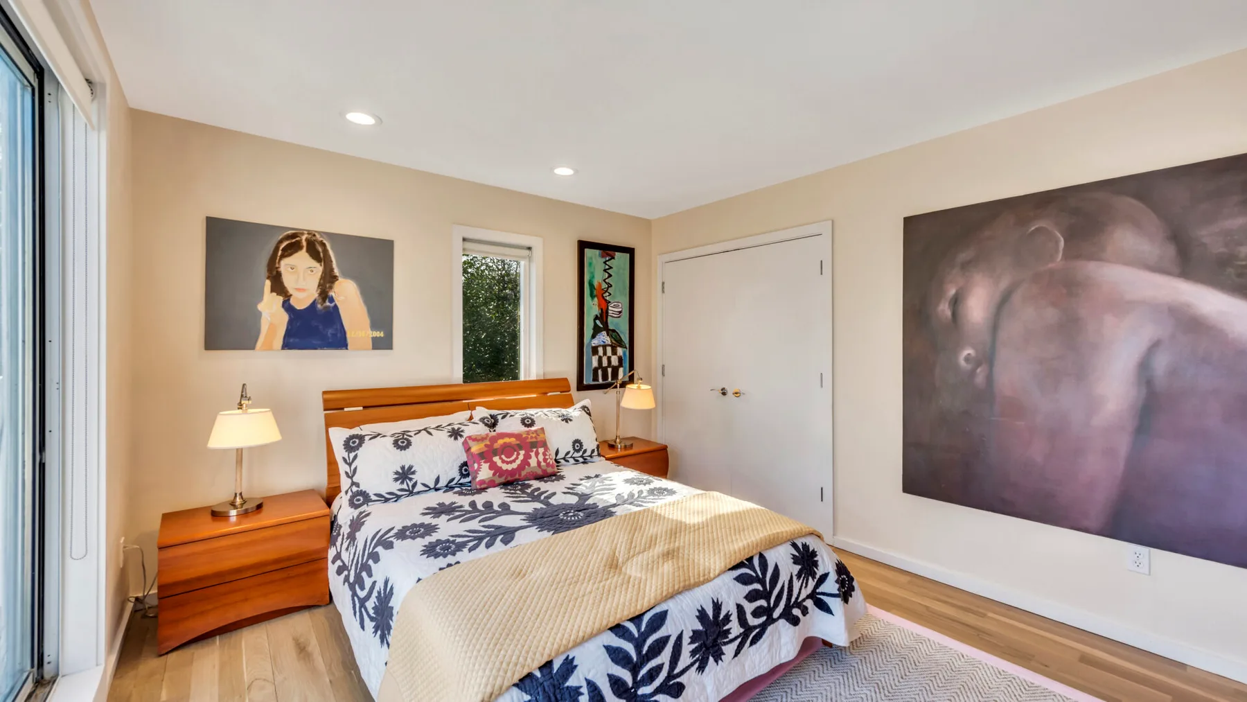 A bedroom with a bed, wooden nightstands, and framed artwork.