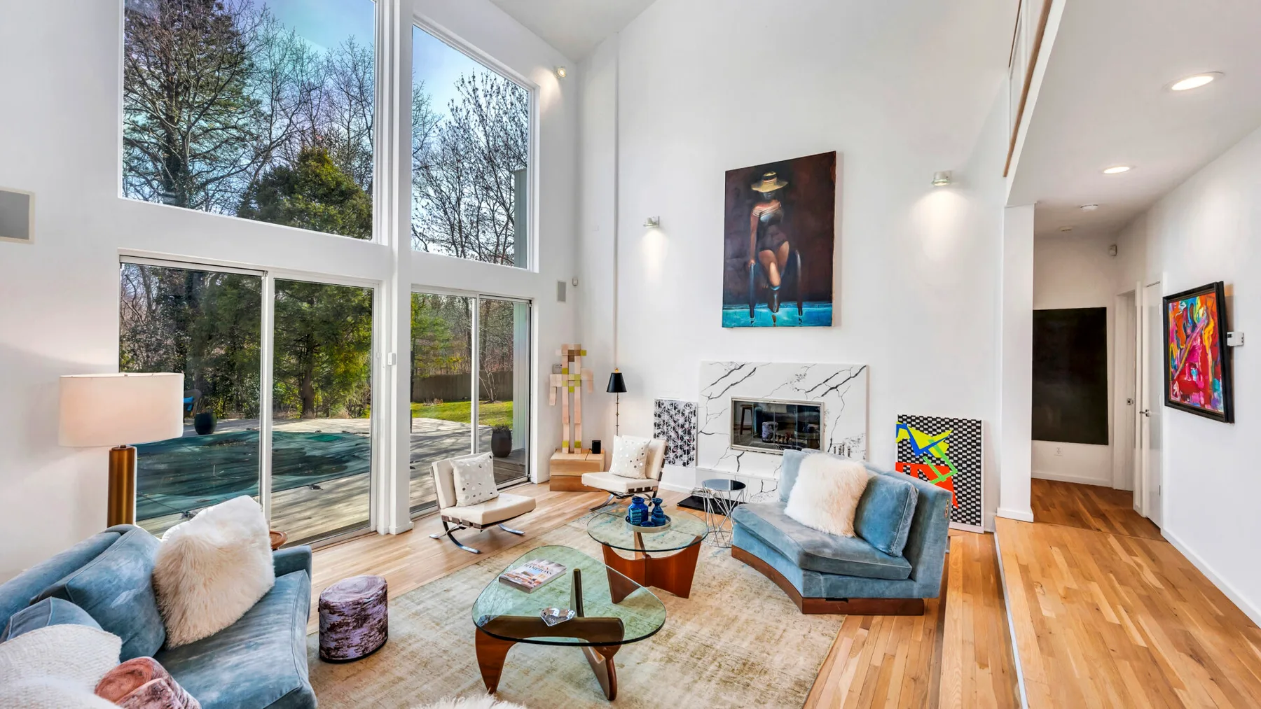A bright living room with tall windows and seating around a coffee table.