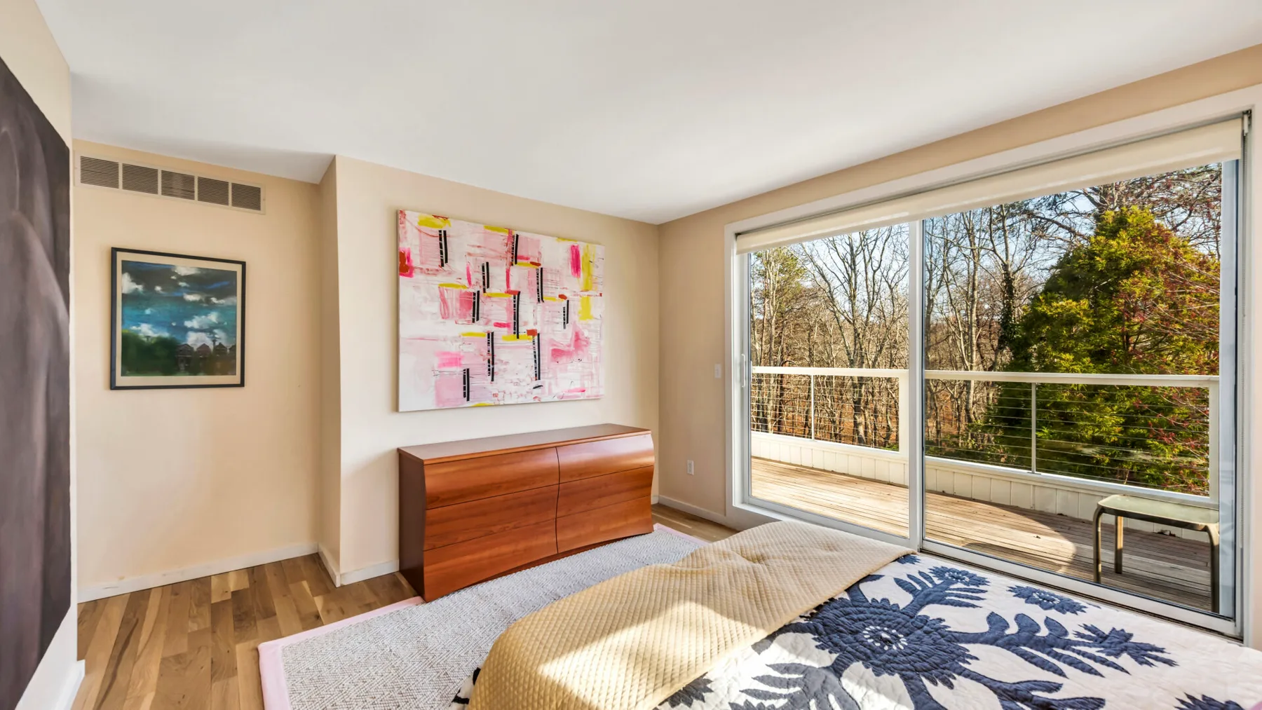 A bedroom with a bed beside large sliding glass doors opening onto a balcony.