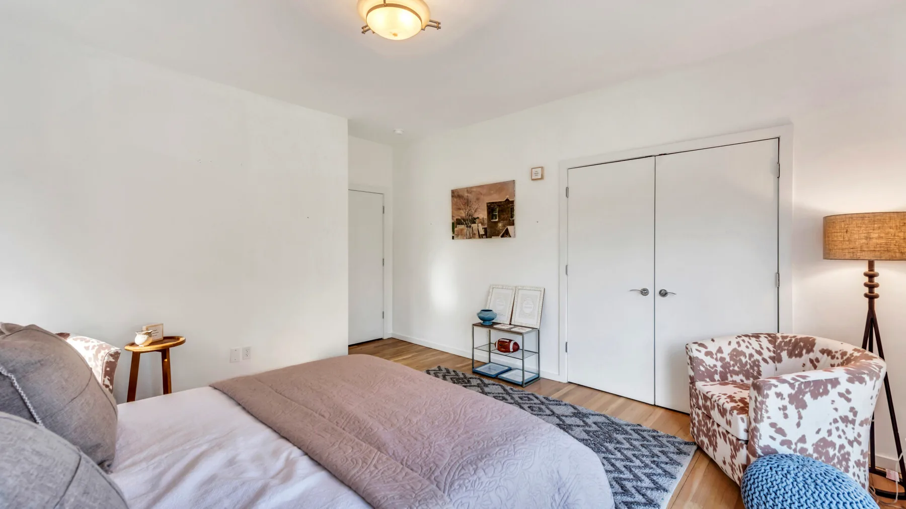 A bedroom with a bed, patterned rug, and armchair.