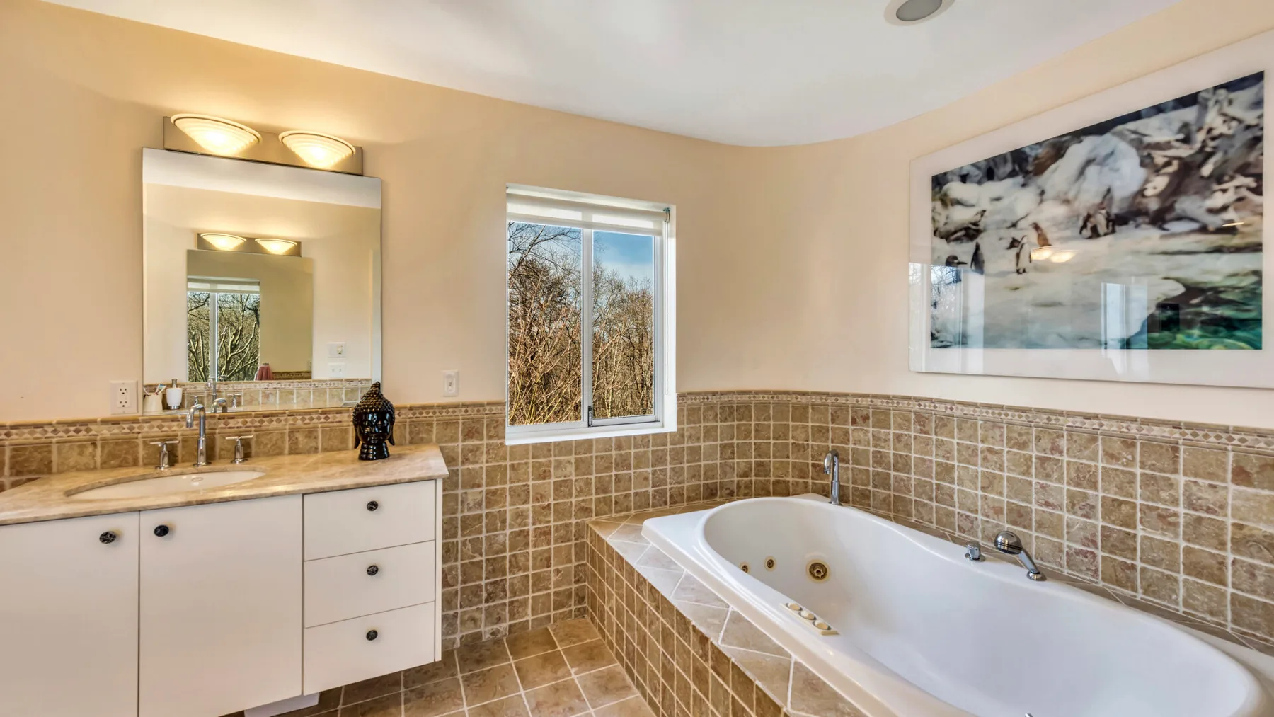 A bathroom with a bathtub, vanity, and window.