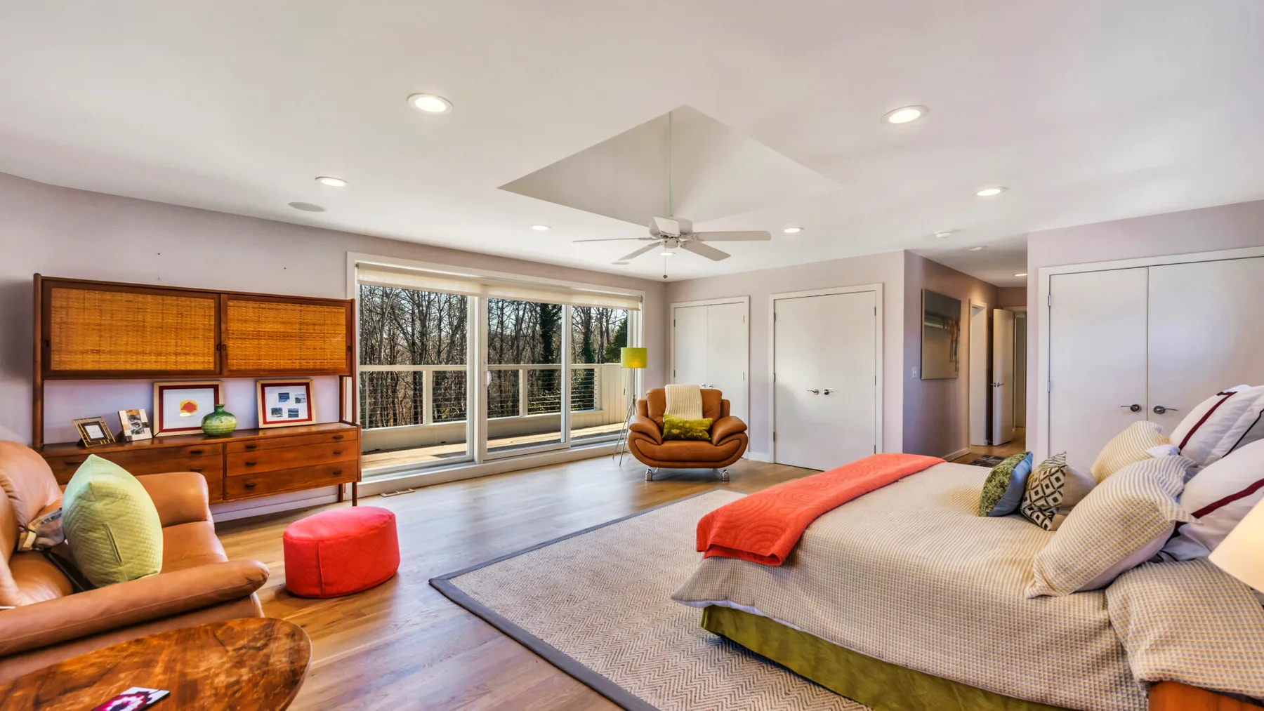 A bright bedroom with a large bed, wide windows, and a sitting area.