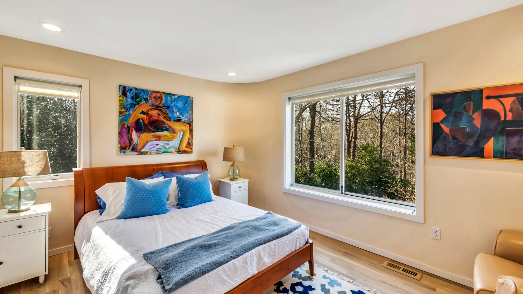 A bedroom with a neatly made bed and colorful artwork on the walls.