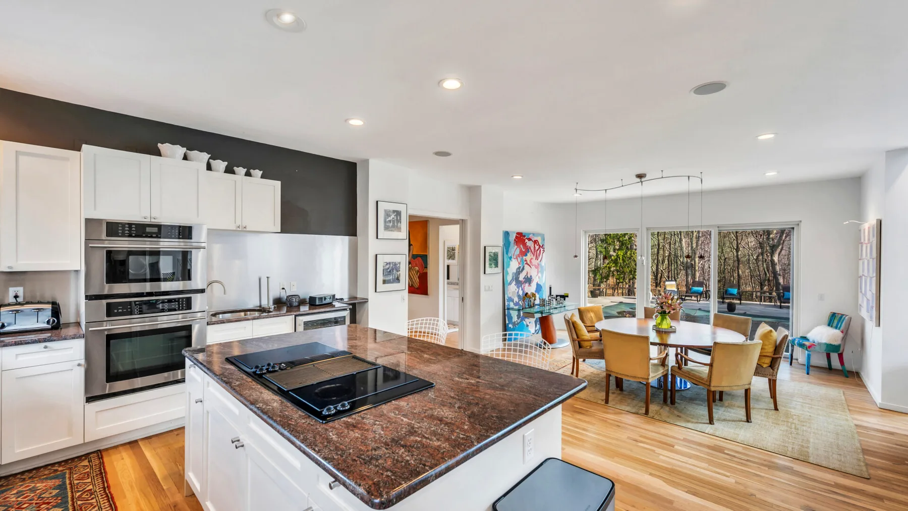 A bright kitchen opens onto a dining area, with a large island in the foreground.